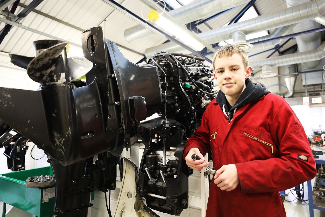Marine engineering student next to outboard motor